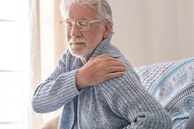 old man holding shoulder in pain because of arthritis