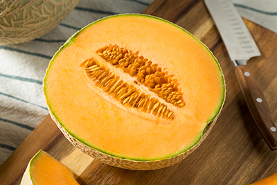 cantaloupe cut in half on wooden cutting board