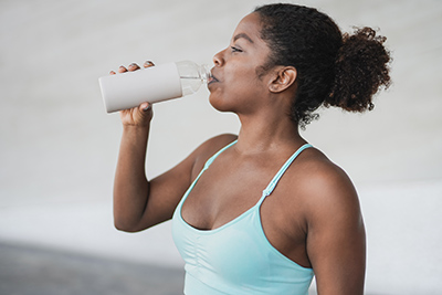 woman drinking water out of sports bottle