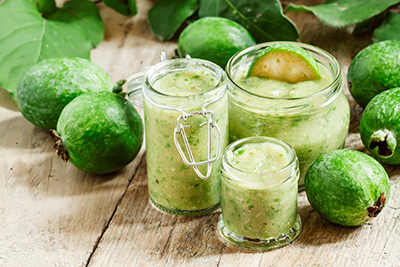 feijoa fruit around glass jars of feijoa smoothies