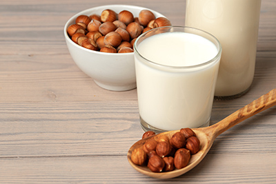 two glasses of horchata and hazelnuts in a wooden spoon