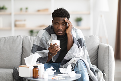 man sitting on couch miserable with the flu