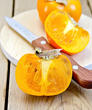 sliced very ripe persimmon with knife visible