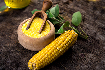 yellow whole corn next to wooden bowl of dry polenta