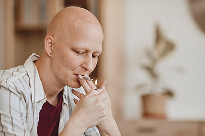 bald woman about to light a cigarette