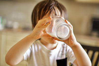 little boy drinking a glass of soymilk