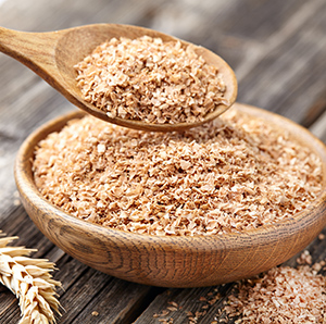 wheat bran in wooden bowl and on wooden spoon