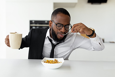 man eating cereal and holding a cup filled with coffee
