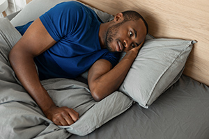 man in bed with eyes open clearly having trouble sleeping