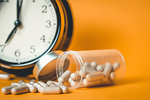 pills spilled on a table with a clock in the background