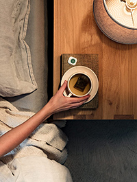 womans hand reaching for a cup of tea on the night table