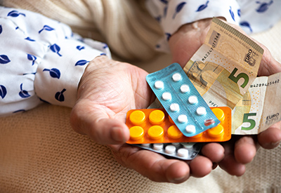 someone holding money along with a variety of medications