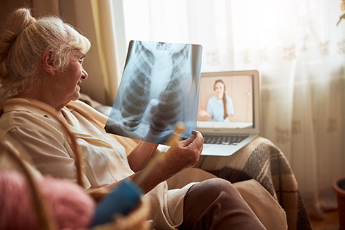 elderly woman sitting on chair watching chest xray