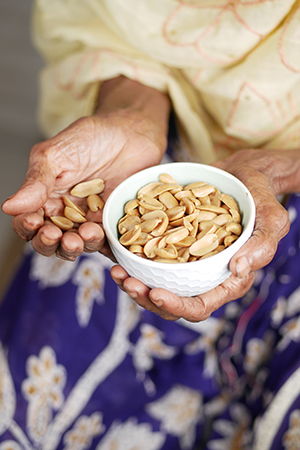 person holding a bowl of peanuts in one hand and peanuts in the other