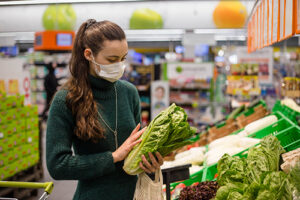 woman shopping and holding leafy greens in her hands