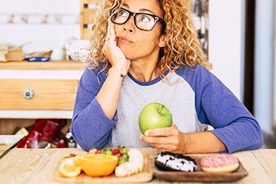 woman sitting with apple in her hand while looking to be in deep thought