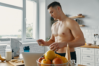 shirtless man in the kitchen about to prepare a healthy shake