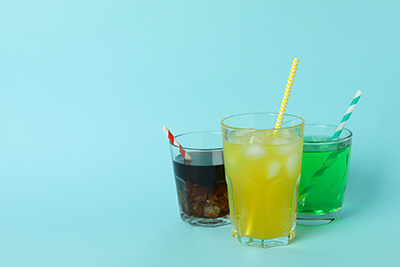 three glasses of different flavor sodas with straws