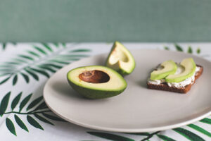 Avocado cut in half on a table with two slices on a sandwich