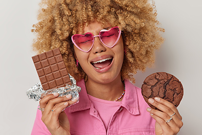 woman holding up a cookie in one hand and a chocolate bar in the other