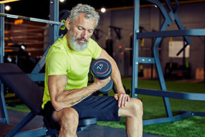 older man doing bicep curls in a gym