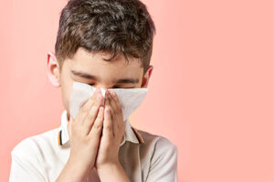 boy blowing his nose into napkin