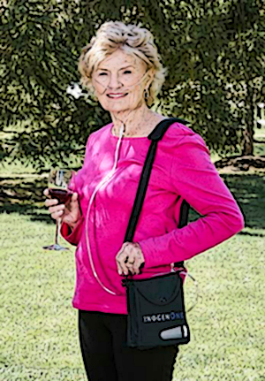 woman happy with her portable oxygen concentrator outdoors holding a glass of wine
