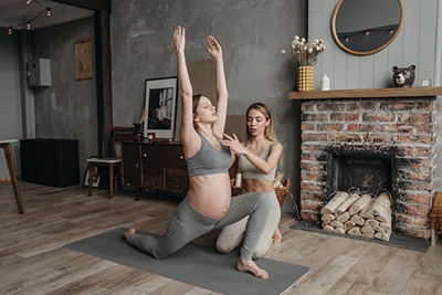 pregnant woman doing yoga with the help of an instructor
