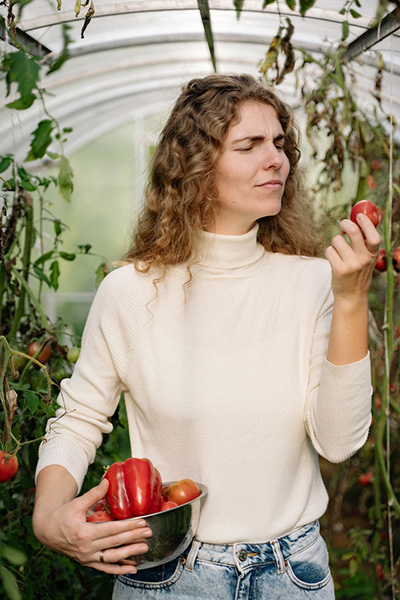 woman with a wide array of fruits and vegetables in a bowl and an apple in her hand