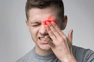 man with hand placed over left eye because of dry tear ducts
