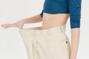 woman admiring weight loss by stretching out pants she's now to small for