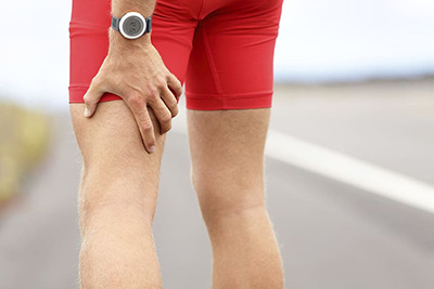 man holding left hamstring after suffering a cramp