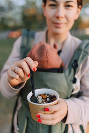 woman showing a cup of healthy nuts and fruits