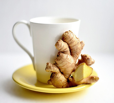 tea cup of ginger tea with a piece of ginger next to it