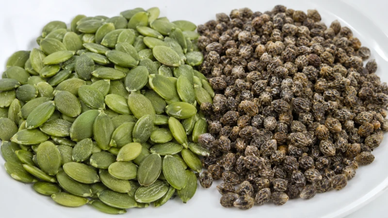 Raw pumpkin seeds with green coating and dried papaya seeds.