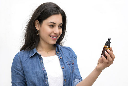 woman looking at vial of milk thistle tincture