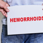 someone holding a sign that reads hemorrhoids behind their but