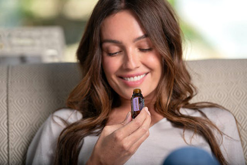woman smiling at a bottle of essential oil