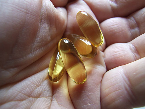 four cod liver oil capsules in someone's hand