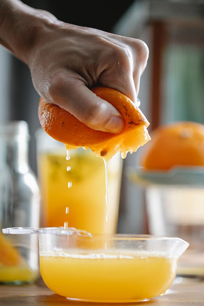someone squeezing an orange into a cup