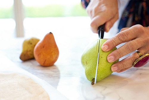 someone cutting a pear in half
