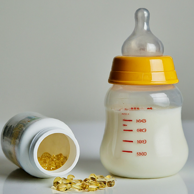 a baby's bottle next to a tipped over bottle of supplements